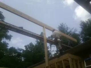 Carpenter setting a ridge beam over a new addition frame — Ice Dam Removal by Roofing Brothers in Long Island