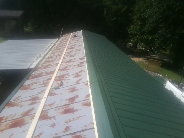 Old rusted panels beside newly installed green metal roofing — Wind Damage Roof Repair by Roofing Brothers in Long Island