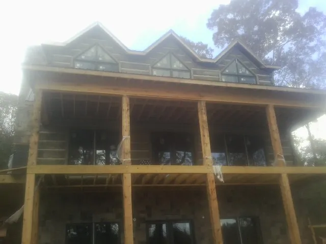 Dormers and porch framing on a large log home under construction — Roof Coating work by our crew in Long Island