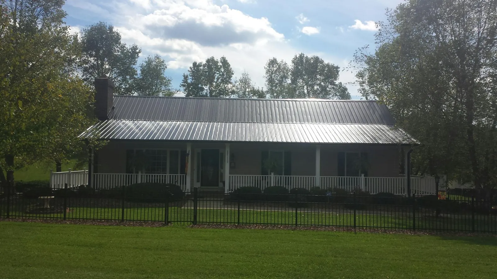 Gray metal roof on a brick ranch with a full width front porch — Gutter Guard Installation work by our crew in Long Island