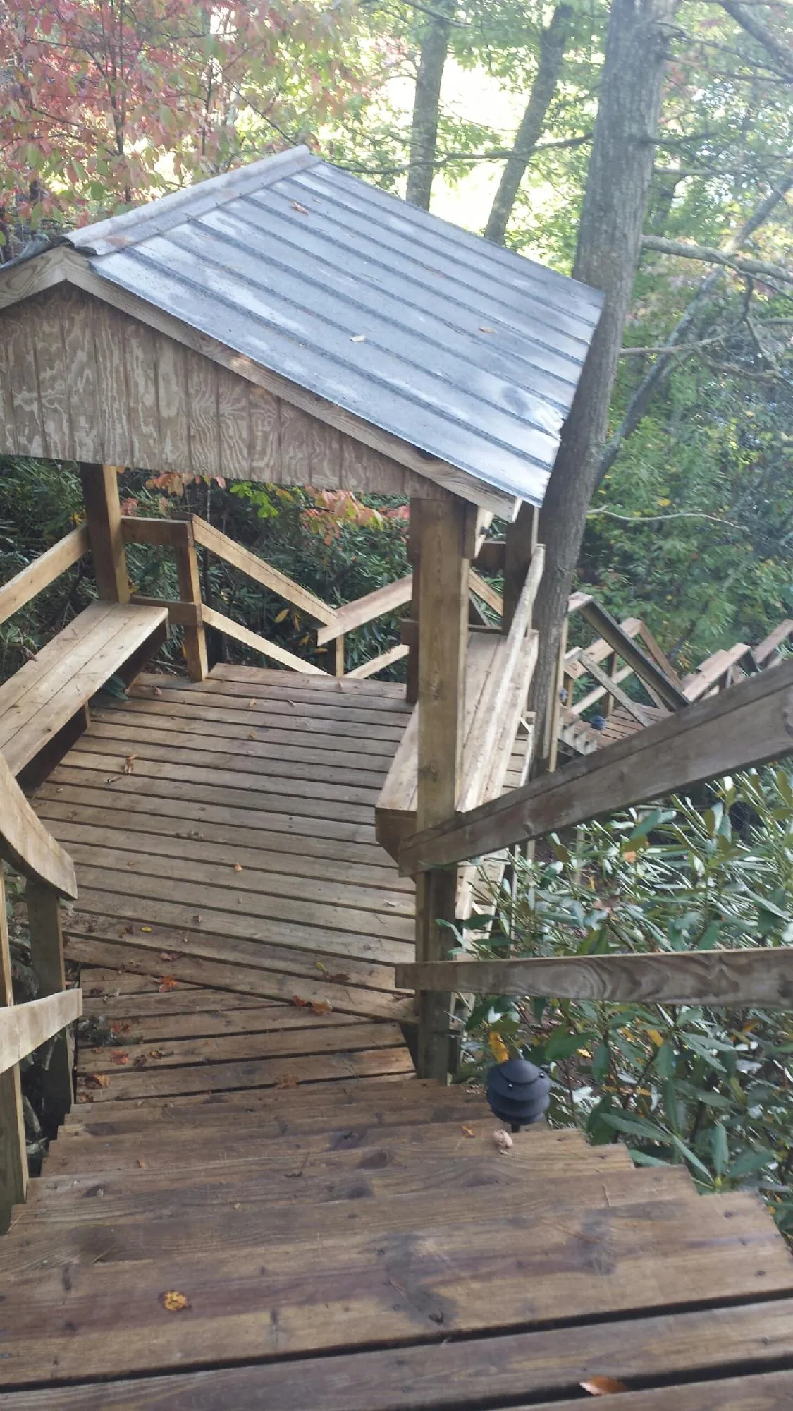 Metal roofed shelter over wooden steps on a wooded walkway — Skylight Repair & Installation work by our crew in Long Island