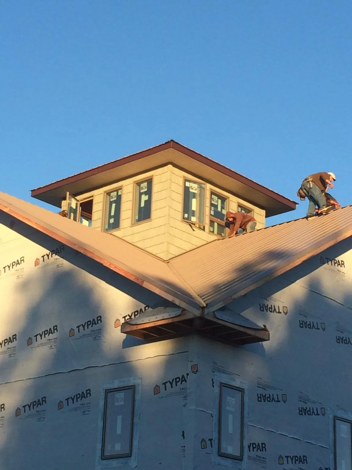 Roofers working around a rooftop cupola on a new metal roof at sunset — Roof Waterproofing in Long Island by Roofing Brothers